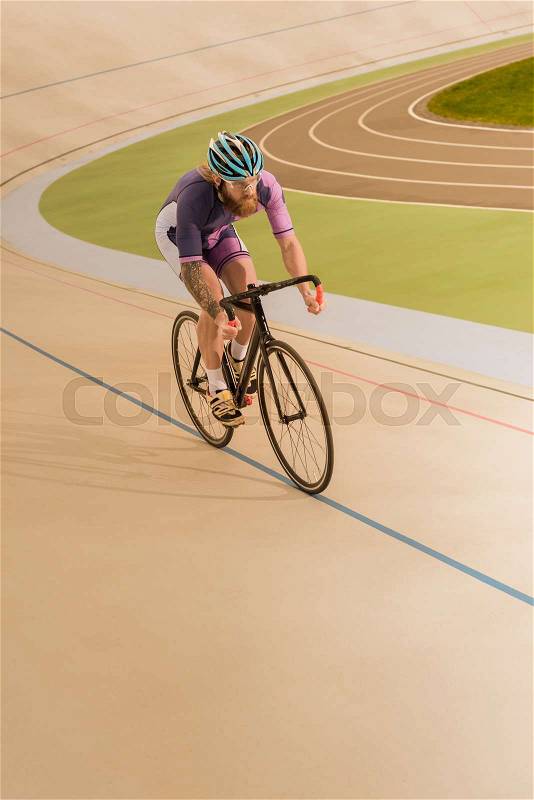 Young cyclist in helmet training on cycle race track, stock photo