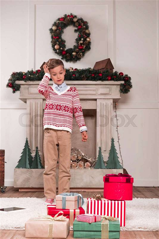 Surprised boy looking at heap of gifts laying on floor, stock photo