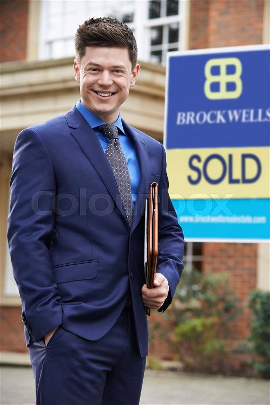 Male Realtor Standing Outside Residential Property With Sold Sign, stock photo