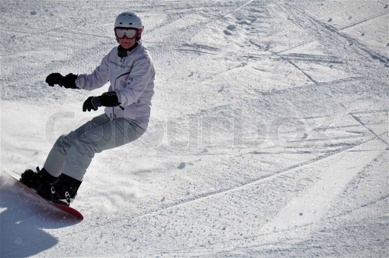 Middle aged female snowboarder wearing helmet and snow goggles in powder snow on steep hill – shot in Livigno, Italian Alps, stock photo