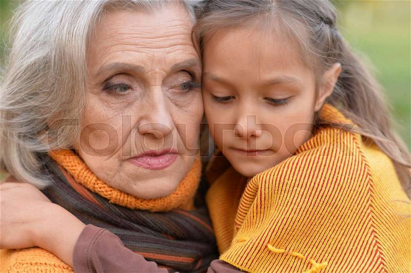 Close up portrait of sad grandmother with granddaughter, stock photo