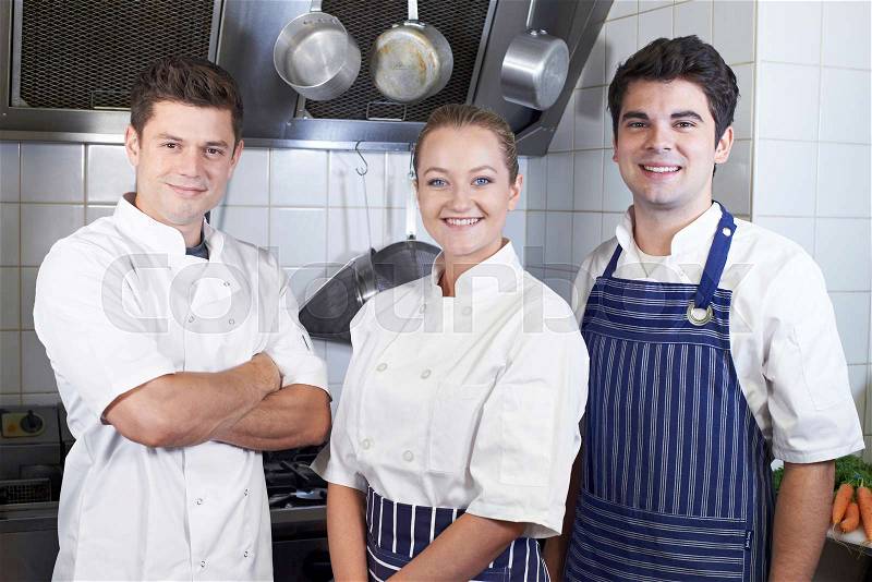 Portrait Of Chef And Staff Standing By Cooker In Kitchen, stock photo