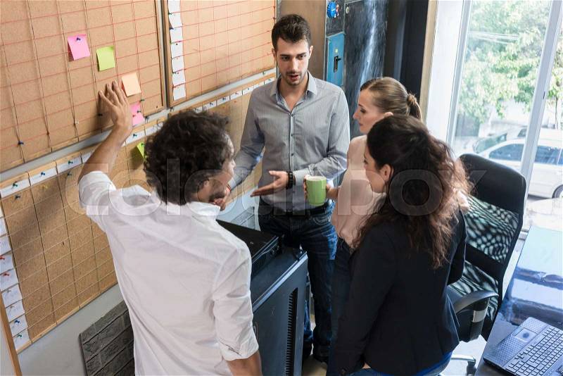 Creative people in agency talking over time planning in meeting, stock photo
