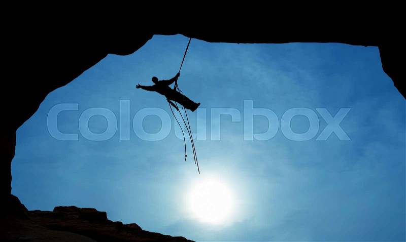 Man rock climber silhouette over blue sky background, stock photo