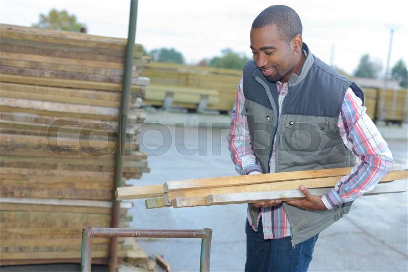 Man carrying wood in materials store, stock photo