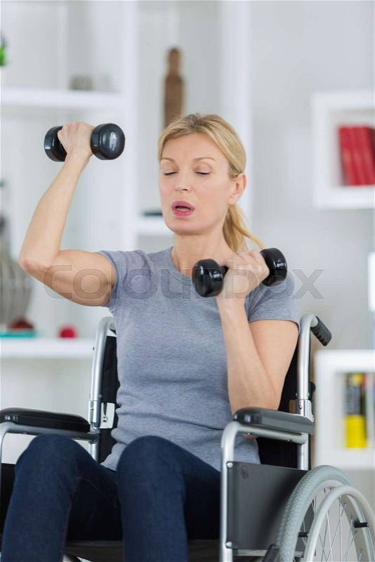Happy disabled person doing exercises with dumbbells, stock photo
