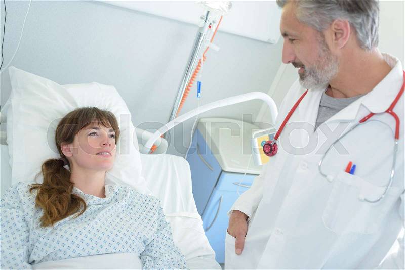 Happy female patient lying on hospital bed, stock photo