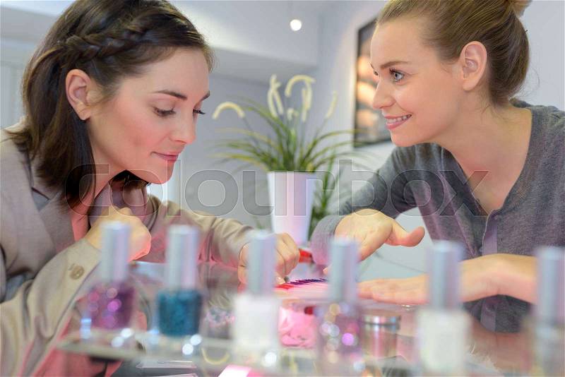 Attractive nail salon worker giving a manicure, stock photo