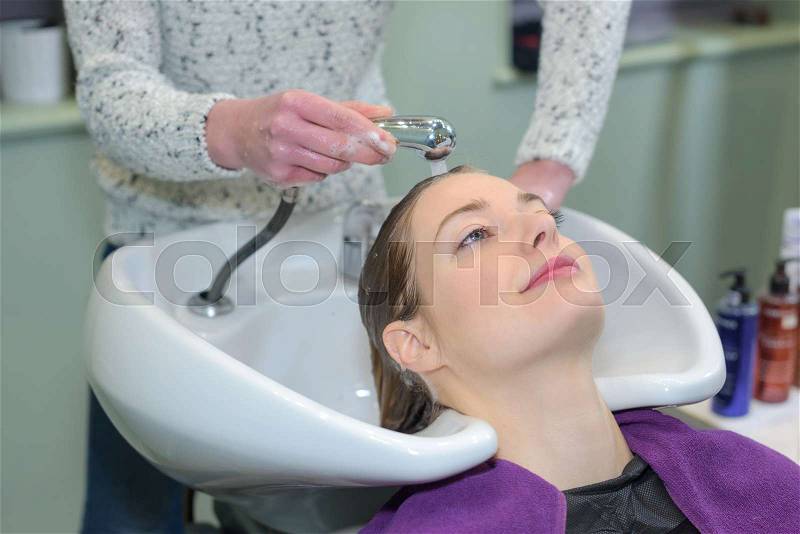Woman having hair washed in salon, stock photo
