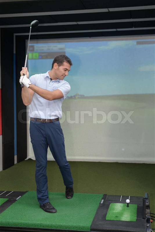 Golfer training with a video game, stock photo