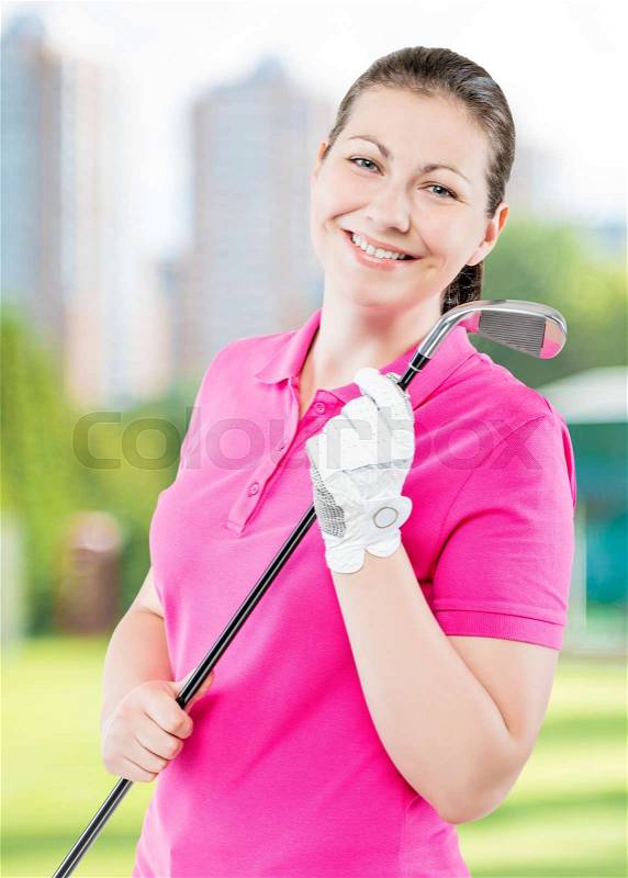 Happy golfer on a background of golf courses smiling and holding a golf club, stock photo