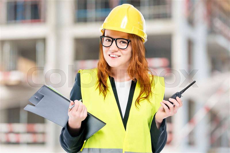 Smiling brigadier woman in protective clothes at construction site, stock photo