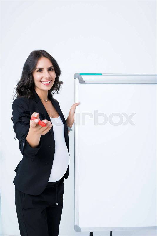 Happy pregnant businesswoman with blank whiteboard pointing at pen, stock photo