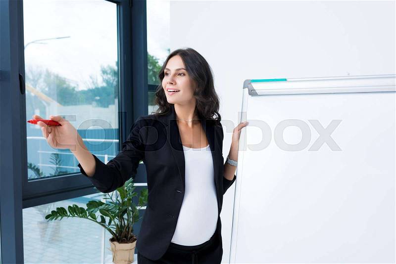 Happy pregnant businesswoman with blank whiteboard and red marker pen, stock photo
