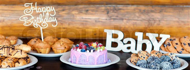 Birthday cakes and muffins with wooden greeting signs on rustic background. Wooden sing with letters Happy Birthday, Baby and holiday sweets, stock photo