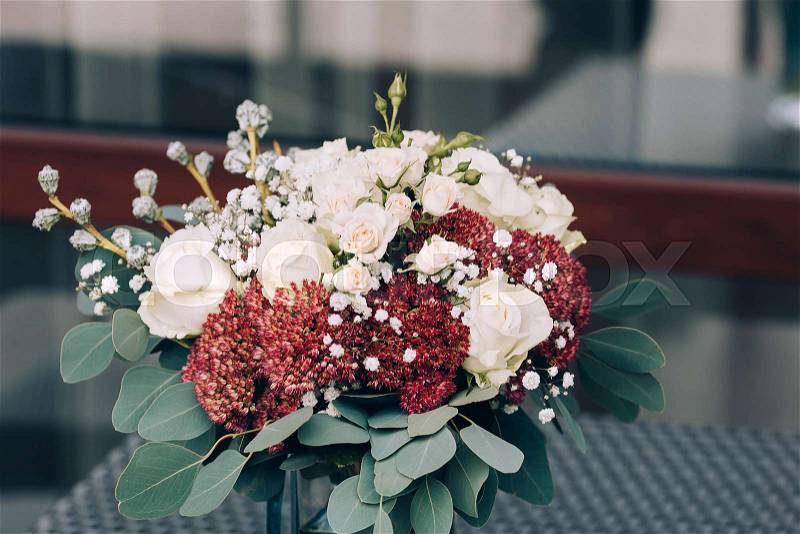 A bouquet of different white and brown flowers in a vase on a wicker table. Close-up. Artwork. Copy space. Outdoors, stock photo