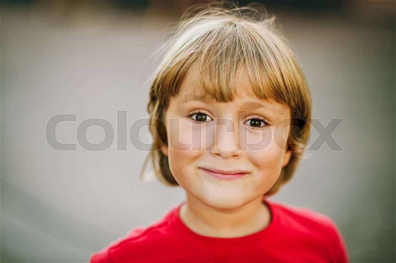 Outdoor close up portrait of adorable 6 year old kid boy, candid facial expression, stock photo