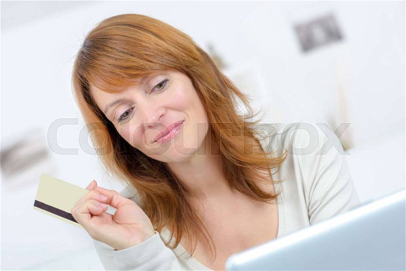 Woman buying on line with bank card and a laptop, stock photo