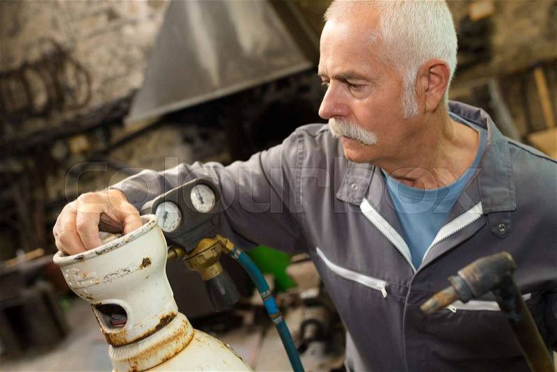 Technician dealing with steel cylinder with gas, stock photo
