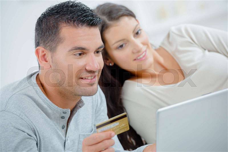 Happy couple with credit card and laptop at home, stock photo