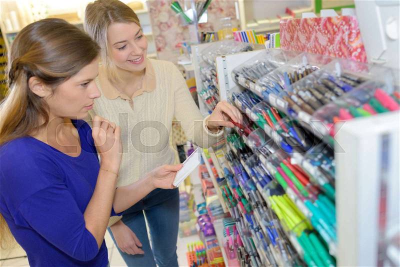 Two women choosing school stationery in the supermarket, stock photo