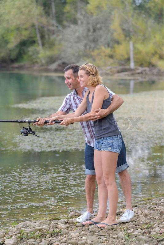 Lovely young couple fishing together by a lake, stock photo