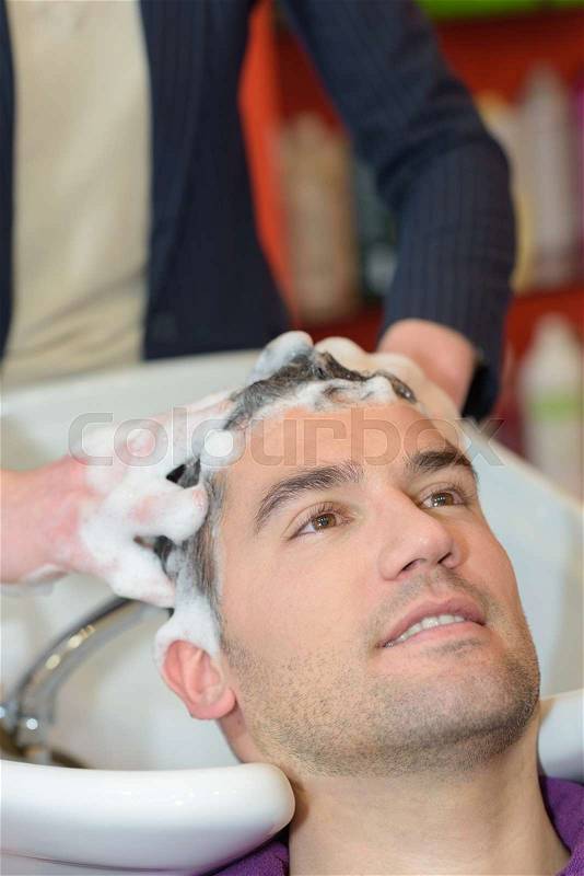 Young man having his hair washed in hairdressing salon, stock photo