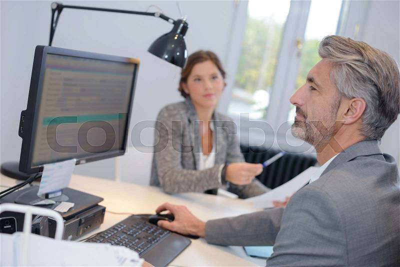 Businessman with personal assistant, looking at computer, stock photo