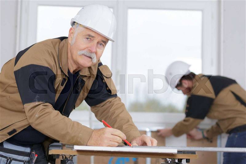 Senior craftsman working with labor protection at carpentry shop, stock photo