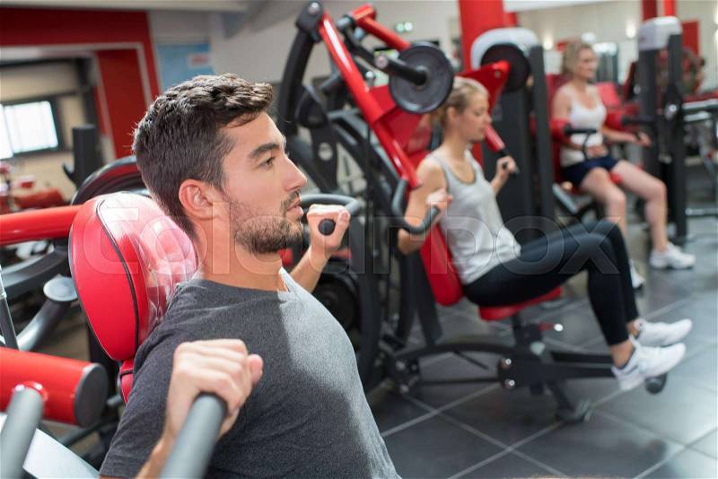 Sport people working out muscles on weight lifting gym machine, stock photo