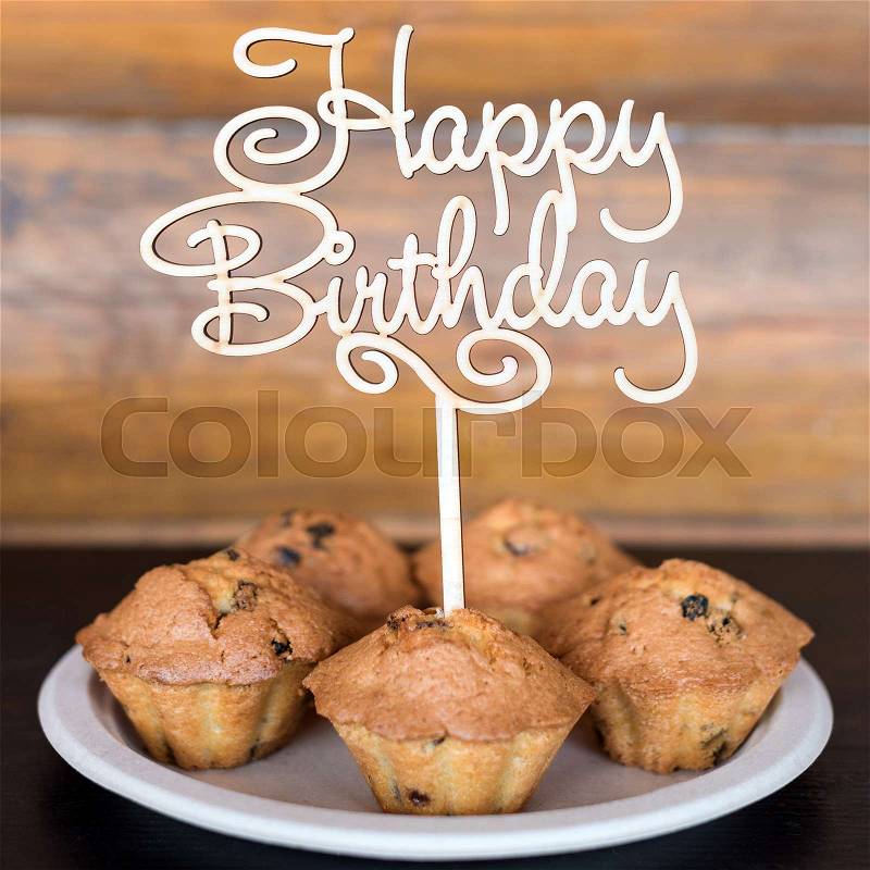Birthday cakes and muffins with wooden greeting sign on rustic background. Wooden sing with letters Happy Birthday and holiday sweets, stock photo