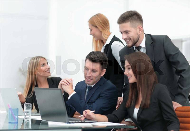 Business team discussing new information , standing in front of the open laptop in the office, stock photo