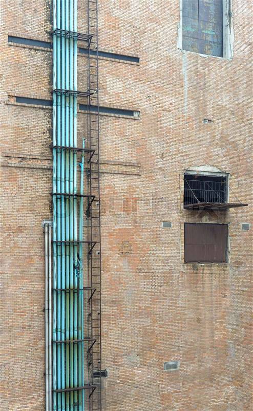 Old brick warehouse building with steel fire escape ladder, stock photo