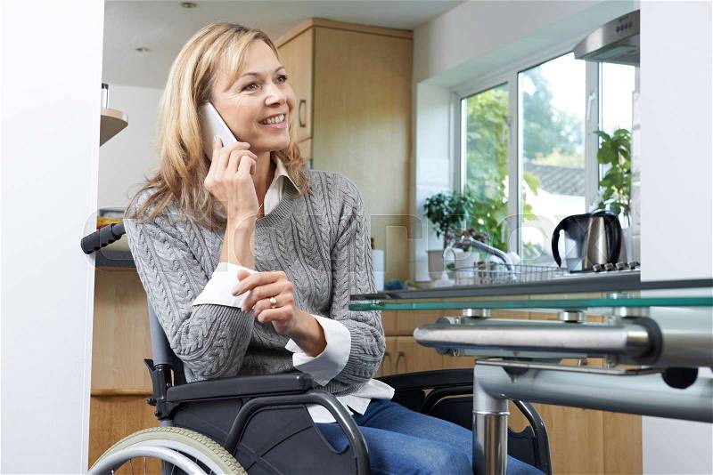 Disabled Woman In Wheelchair Talking On Mobile Phone At Home, stock photo