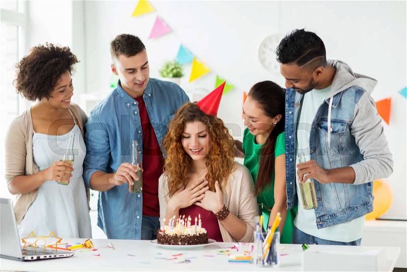 Corporate, celebration and people concept - happy team with birthday cake and non-alcoholic drinks greeting colleague at office party, stock photo