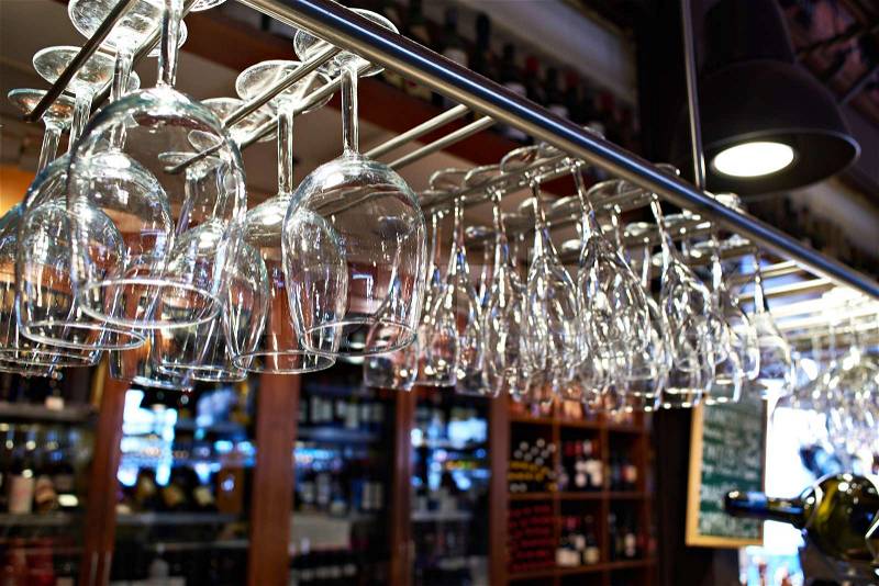 Empty wine glasses hanging above the bar counter, stock photo