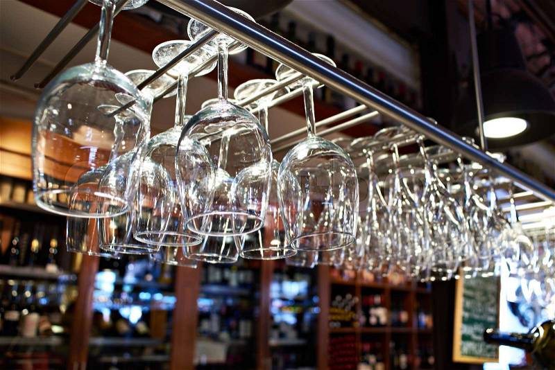 Empty wine glasses hanging above the bar counter, stock photo