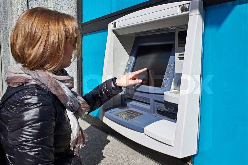 Woman uses touchscreen on ATM, stock photo