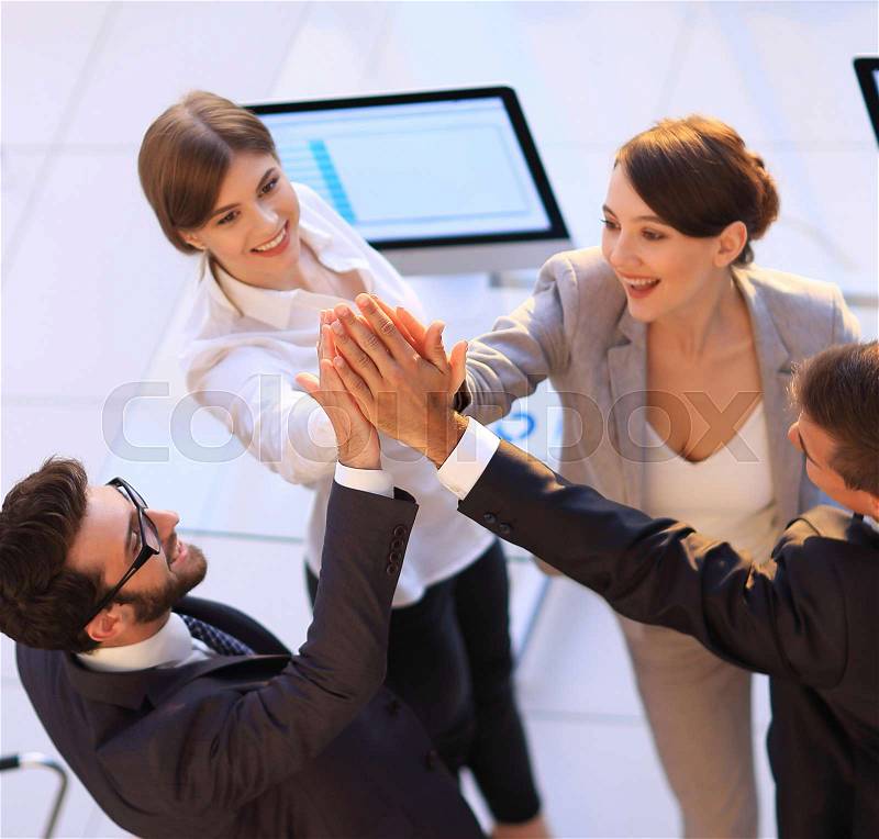 Successful business team giving each other a high-five, standing in the office.concept of success, stock photo
