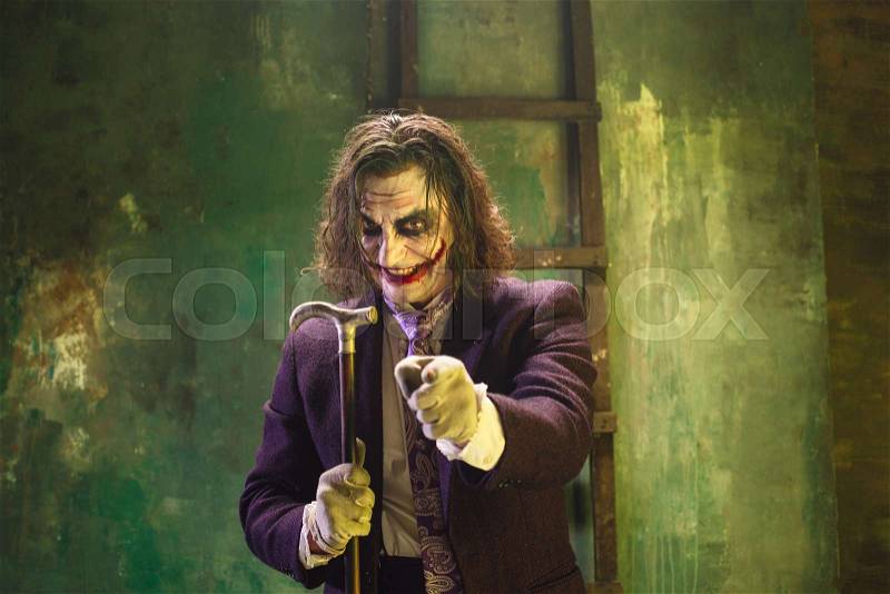 Bloody Halloween theme: The crazy joker face on dark studio background, stock photo
