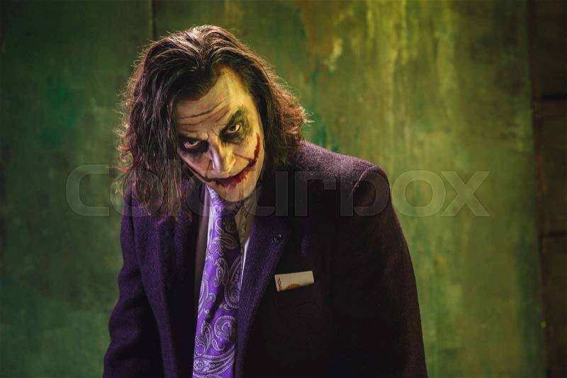 Bloody Halloween theme: The crazy joker face on dark studio background, stock photo
