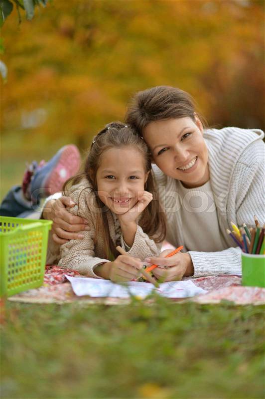 Little cute girl with her mother drawing together in park, stock photo