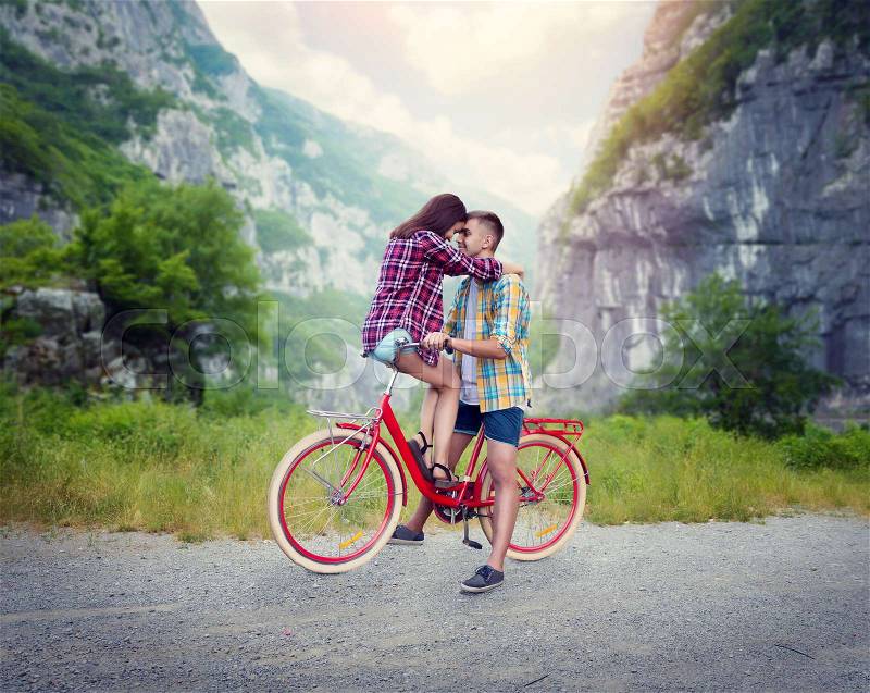 Boyfriend and girlfriend kissing on retro bike. Love couple with vintage bicycle. Young man and woman happy together outdoor, nature on background, stock photo