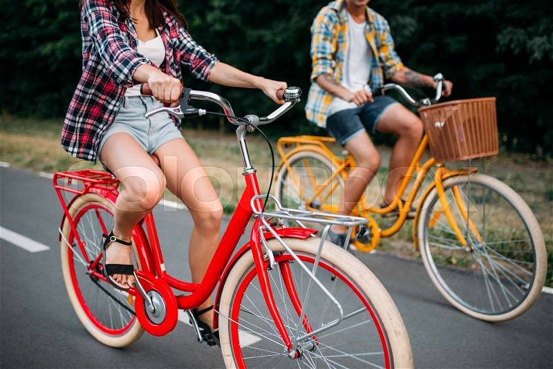 Male and female persons riding on retro bikes. Couple on vintage bicycles. Young man and woman on old cycles, stock photo