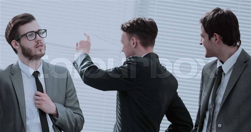 Company Director and business team in business suits and ties standing in the office near the window and talking, stock photo