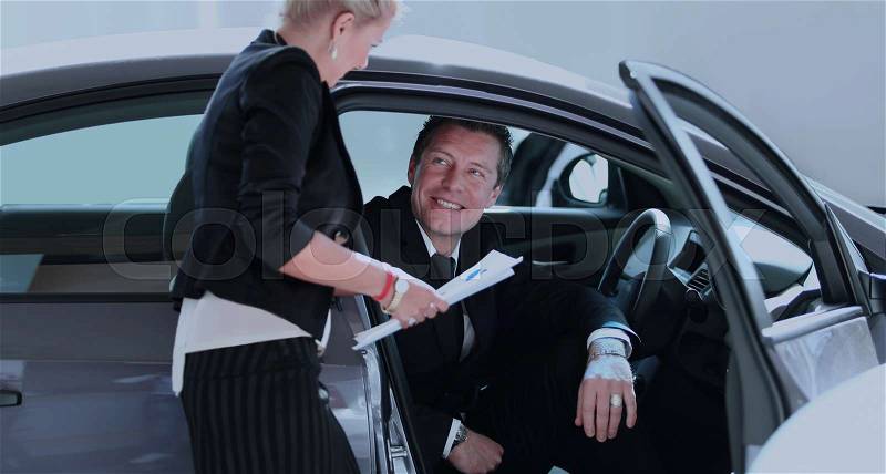 Handsome successful man buying a car at dealership, stock photo