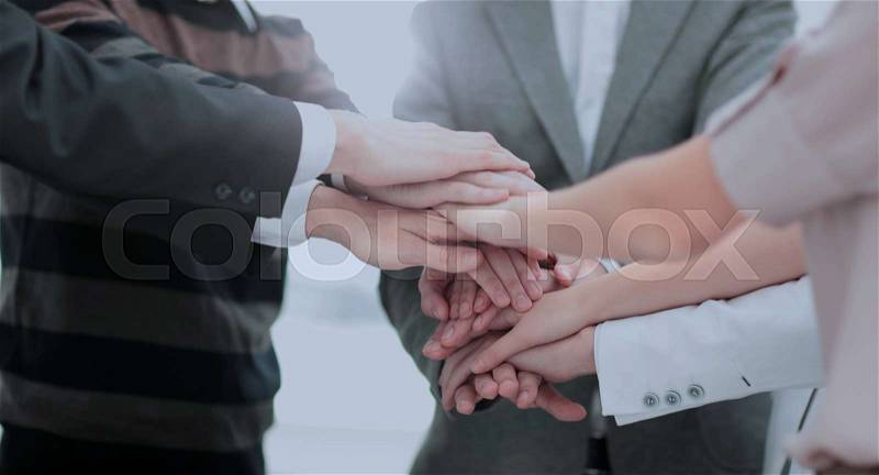 Close-up of business partners making pile of hands at meeting, stock photo