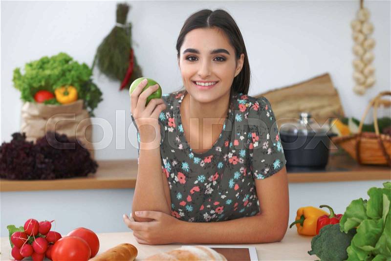 Young hispanic woman or student cooking in kitchen. Girl using tablet to make online shopping or find a new recipe, stock photo