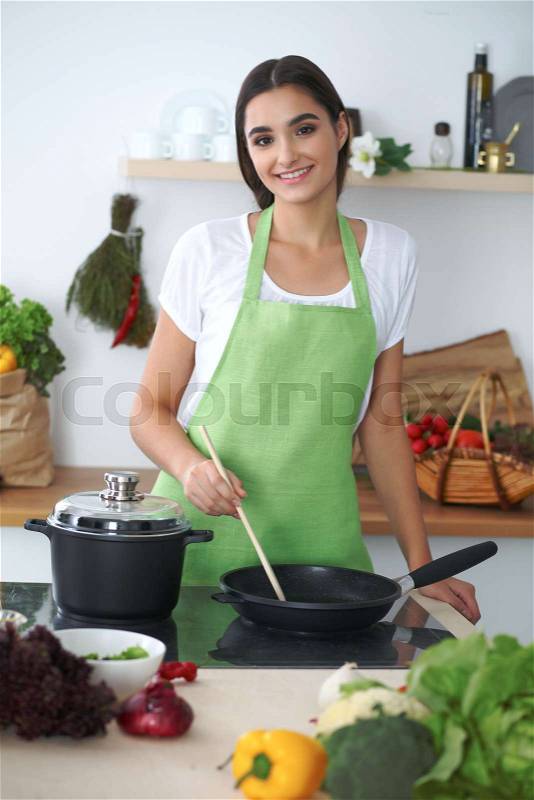 Young hispanic woman or student cooking in kitchen, stock photo