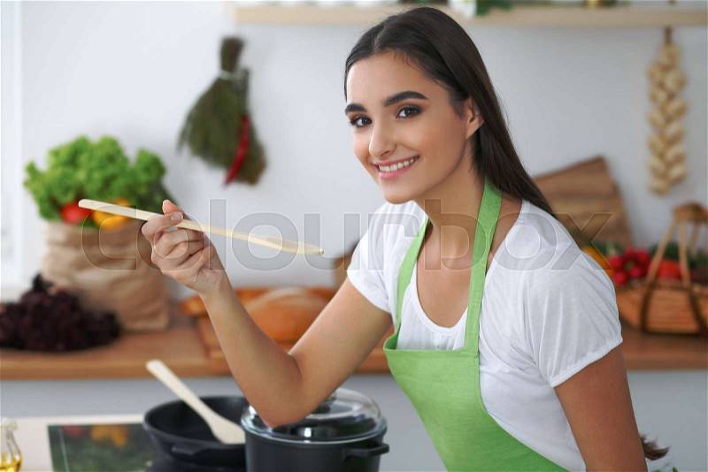 Young hispanic woman or student cooking in kitchen, stock photo
